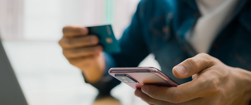 Decorative image - Person holding credit card about to make transaction on mobile