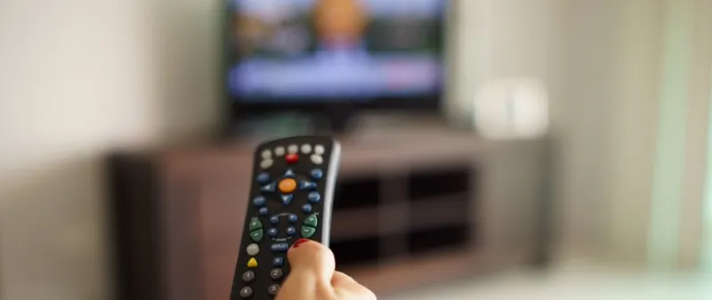 Decorative image - Woman holding remote watching TV news