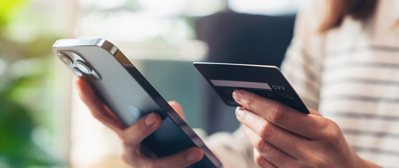 Decorative image - Person holding credit card and mobile phone, looking at both