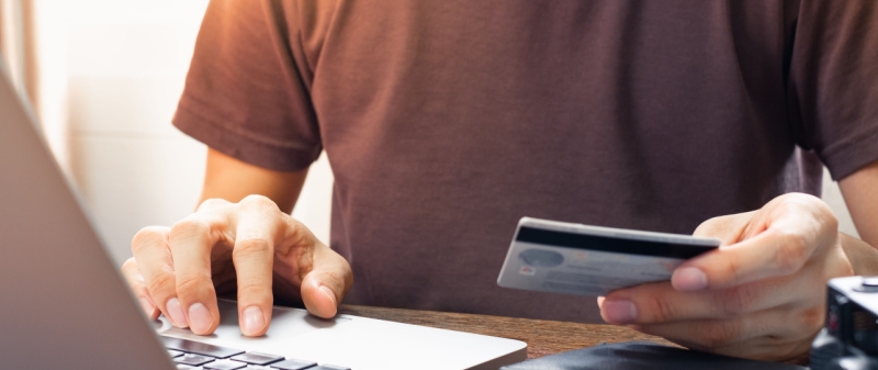 Decorative image - Man with credit card typing on laptop