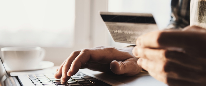 Decorative image - Man with credit card typing on laptop