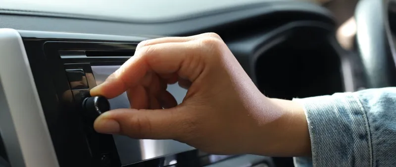 Decorative image - Person turning dial on car radio