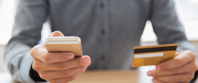 Decorative image - Man using mobile phone holding credit card
