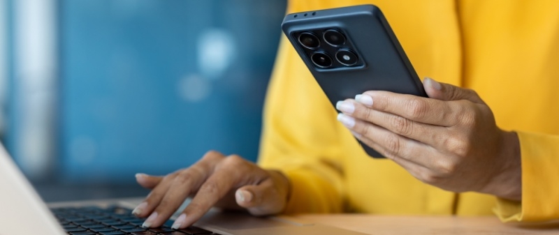 Decorative image - Woman holding phone and typing on computer