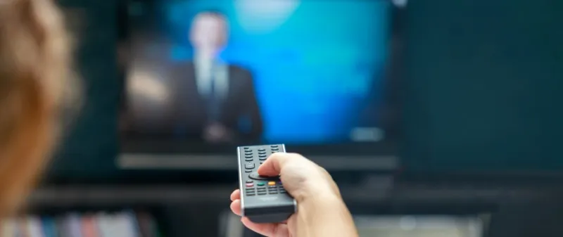 Decorative image - Woman with remote control watching TV