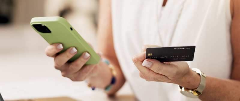 Decorative image - Person holding credit card and looking at mobile