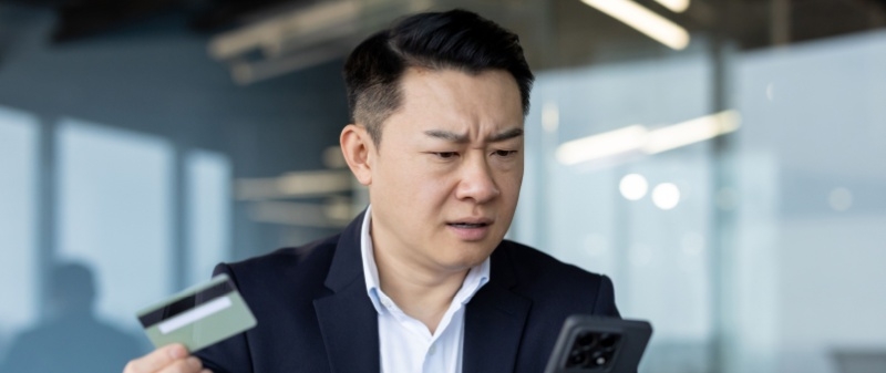 Decorative image - Concerned man holding credit card and mobile