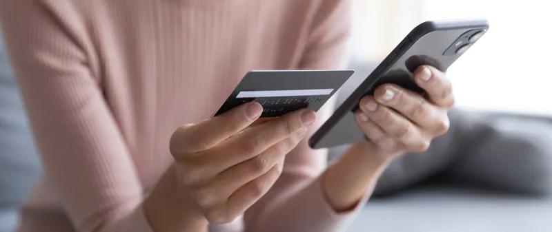 Decorative image - Woman looking at credit card and mobile phone