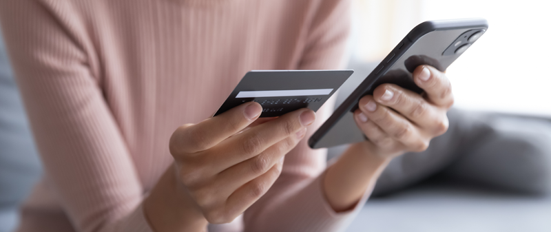 Decorative image - Woman looking at credit card and mobile phone