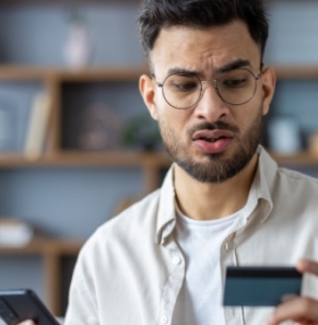 Decorative image - Concerned man looking at credit card and phone