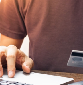 Decorative image - Man with credit card typing on laptop