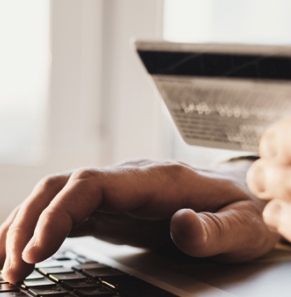 Decorative image - Man with credit card typing on laptop
