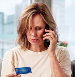 Decorative image - Woman on mobile phone referring to credit card in her hand