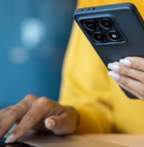 Decorative image - Woman holding phone and typing on computer