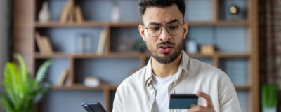 Decorative image - Concerned man looking at credit card and phone