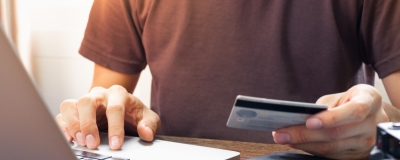 Decorative image - Man with credit card typing on laptop