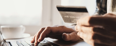 Decorative image - Man with credit card typing on laptop