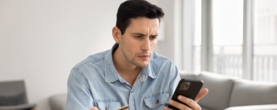Decorative image - Concerned man holding credit card and looking at mobile phone