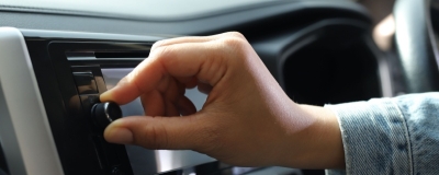 Decorative image - Person turning dial on car radio