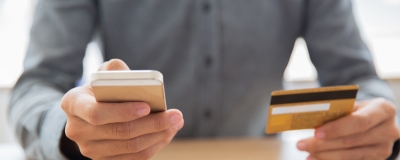 Decorative image - Man using mobile phone holding credit card