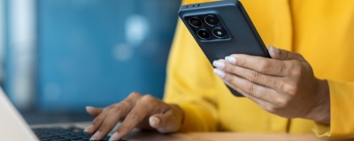 Decorative image - Woman holding phone and typing on computer