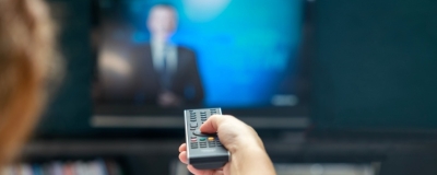 Decorative image - Woman with remote control watching TV