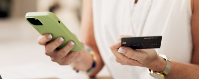 Decorative image - Person holding credit card and looking at mobile