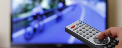 Decorative image - Person holding television remote watching professionsal cycling