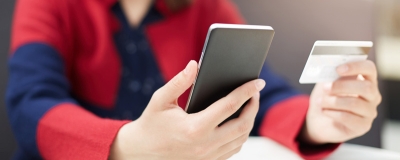 Decorative image - Person looking at mobile phone and credit card